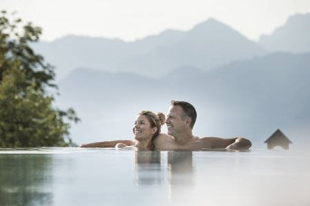Ein Paar entspannt im Außenpool im Familotel Allgäuer Berghof.