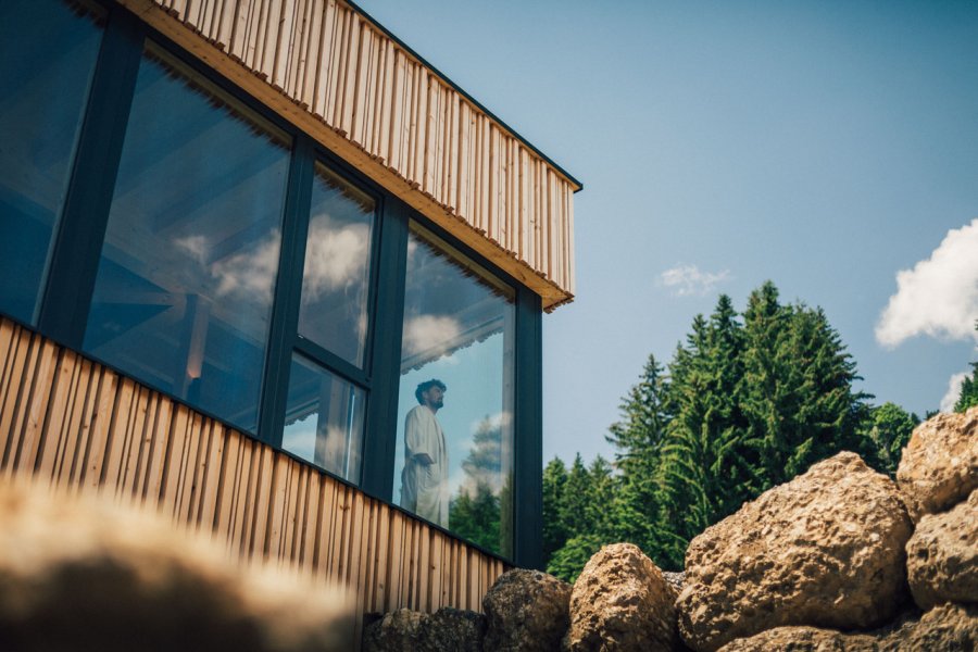 Ein Mann blickt aus einem Fenster im Wellnessbereich im Torgheles Wald und Fluh in Balderschwang.