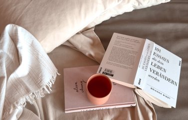 Eine Tasse Kaffee und Bücher liegen auf einem Bett im Torgheles Wald und Fluh in Balderschwang.