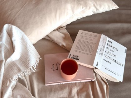 Eine Tasse Kaffee und Bücher liegen auf einem Bett im Torgheles Wald und Fluh in Balderschwang.