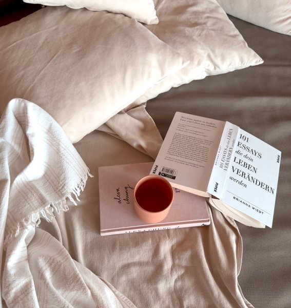 Eine Tasse Kaffee und Bücher liegen auf einem Bett im Torgheles Wald und Fluh in Balderschwang.