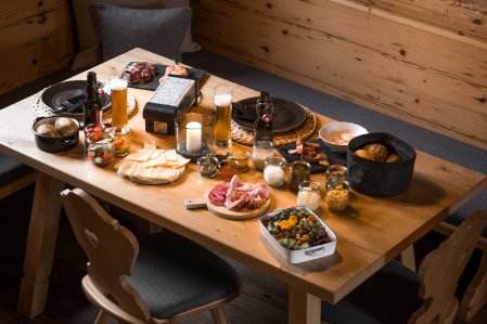 Auf einem Tisch in den Alpzitt Chalets in Burgberg steht alles bereit für ein leckeres Raclette.