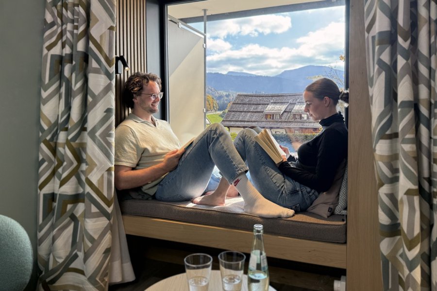Bayerischer Hof Zimmer Ein Paar sitzt auf dem Fensterbrett und ließt ein Buch im Hotel Bayerischer Hof in Oberstaufen.