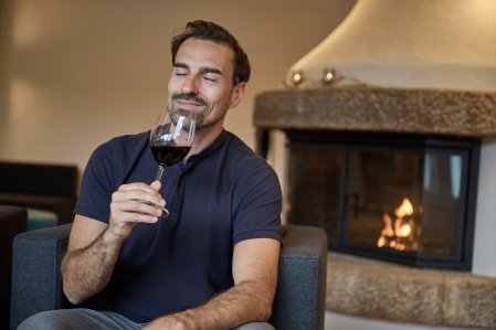 Ein Gast trinkt einen Wein am Kamin in SCHÜLE'S Gesundheitsresort & Spa in Oberstdorf.