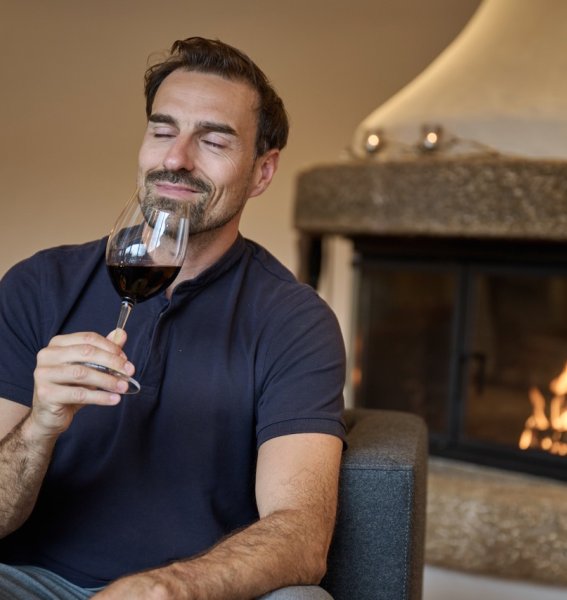 Ein Gast trinkt einen Wein am Kamin in SCHÜLE'S Gesundheitsresort & Spa in Oberstdorf.