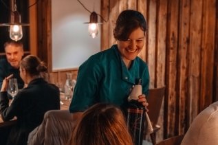 Eine Kellnerin serviert einen Wein im Wald & Wiesn Berghotel Balderschwang.