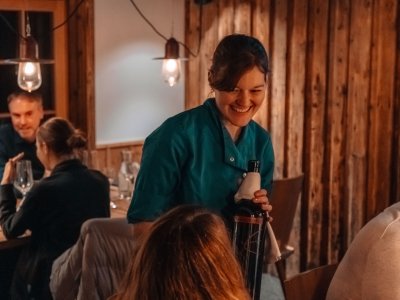 Wald & Wiesn Berghotel Balderschwang Restaurant Eine Kellnerin serviert einen Wein im Wald & Wiesn Berghotel Balderschwang.