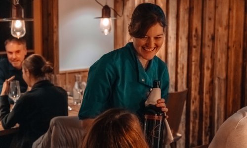 Wald & Wiesn Berghotel Balderschwang Restaurant Eine Kellnerin serviert einen Wein im Wald & Wiesn Berghotel Balderschwang.