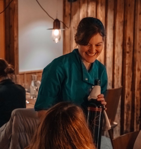 Wald & Wiesn Berghotel Balderschwang Restaurant Eine Kellnerin serviert einen Wein im Wald & Wiesn Berghotel Balderschwang.