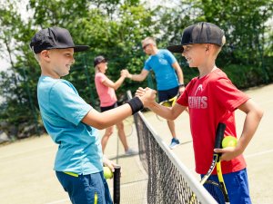 Kinder und ihre Eltern schlagen jeweils für ein Matsch auf dem Tennisplatz im Allgäuer Berghof in Gunzesried ein