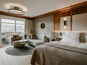 Einblick in eines der modernen und gemütlichen Zimmer im Bergkristall - Mein Resort im Allgäu in Oberstaufen mit Blick auf das Doppelbett und eine Sitzniesche