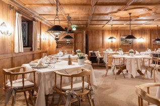 Gemütliche Stube in einem der Restaurants im Sonnenalp Resort in Ofterschwang mit Holzverkleidung und festlicher Tischdekoration
