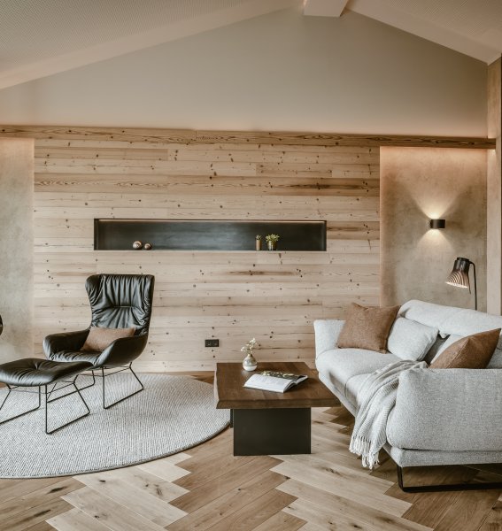 Natursuite im Bergkristall - Mein Resort im Allgäu in Oberstaufen mit Blick auf eine gemütliche und moderne Sitzgelegenheit in warmen Tönen und einen brennenden Kamin