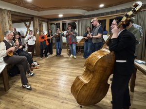 Mehrere Personen mit Instrumenten stehen im Kreis in der Kaminhalle im Hotel Prinz-Luitpold-Bad in Bad Hindelang im Kreis zusammen und musizieren