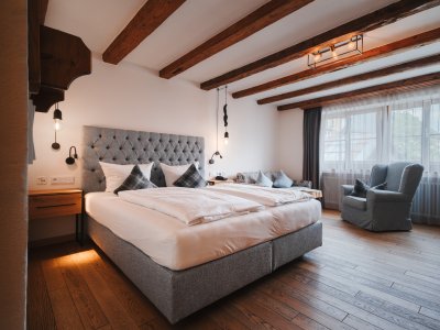 Hotel Restaurant Adler Doppelzimmer Blick auf ein modernes Doppelzimmer mit großem Doppelbett, schöner Holzboden und bequemem Sessel.