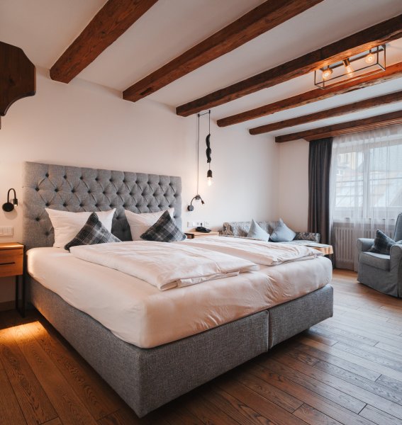Hotel Restaurant Adler Doppelzimmer Blick auf ein modernes Doppelzimmer mit großem Doppelbett, schöner Holzboden und bequemem Sessel.