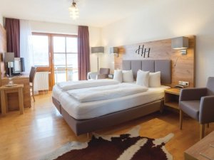 Einblick in eines der Zimmer im Hartungs Hoteldorf in Hopfen am See mit Blick auf ein Doppelbett