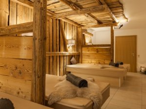 Gemütliche Liegen mit viel Holz und mit Schaffellen dekoriert im Wellnessbereich des Hartungs Hoteldorf in Hopfen am See