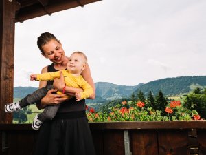 Eine Frau mit ihrem Baby auf dem Balkon im Mondi Resort Oberstaufen.
