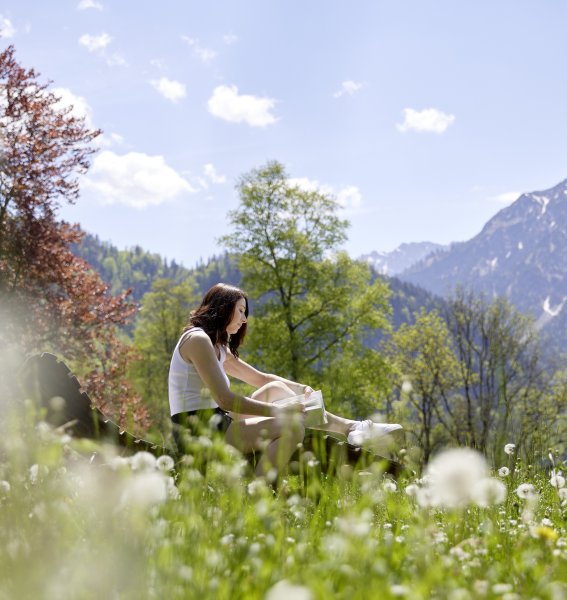 Eine Dame liest ein Bucht auf einer liege inmitten von Pusteblumen im Hotel Prinz-Luitpold-Bad in Bad Hindelang.
