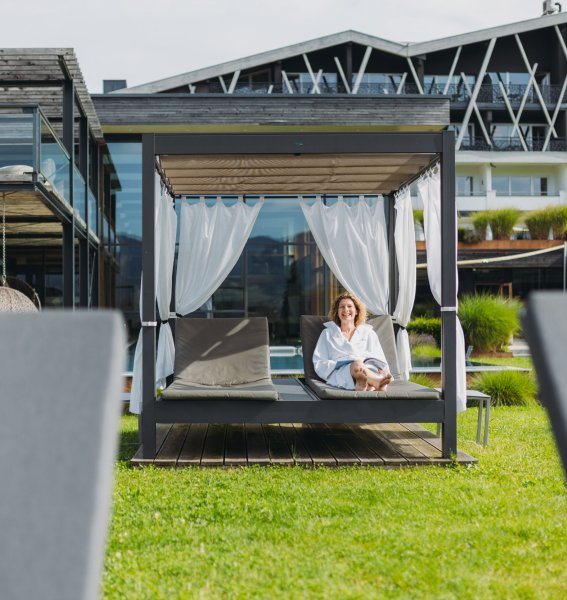 Eine Dame entspannt auf einem Daybed im Garten des Rosenalp Gesundheitsresort & Spa in Oberstaufen.