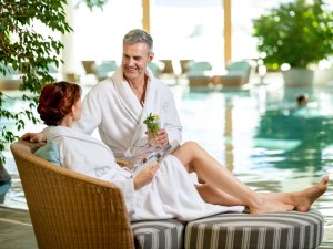 Ein Paar liegt gemeinsam auf einer Liege am Rande des Innenpools im Sonnenalp Resort in Ofterschwang