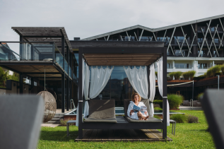 Eine Dame entsapnnt auf einem Day Bed im Garten des Rosenalp Gesundheitsresort & Spa in Oberstaufen.