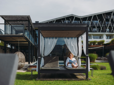 Eine Dame entsapnnt auf einem Day Bed im Garten des Rosenalp Gesundheitsresort & Spa in Oberstaufen.