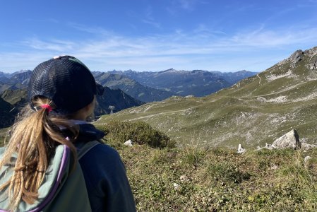 Ein Kind von hinten beim Wandern in der Allgäuer Bergwelt in der Nähe vom Hotel Hahnenköpfle in Oberstdorf