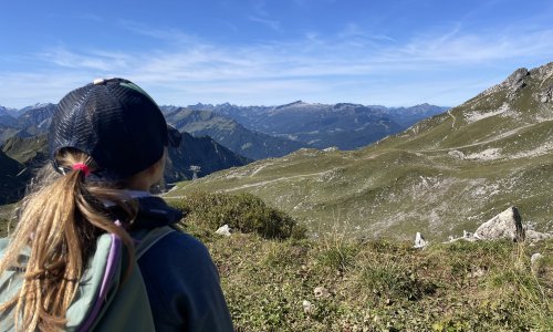 Ein Kind von hinten beim Wandern in der Allgäuer Bergwelt in der Nähe vom Hotel Hahnenköpfle in Oberstdorf