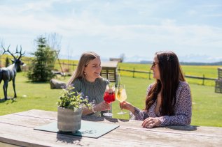 Freundinnen genießen einen Aperitif auf der Terrasse des Weitblick Allgäu in Marktoberdorf.