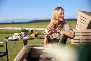Eine Dame frühstückt auf der Terrasse im Weitblick Allgäu in Marktobderdorf.