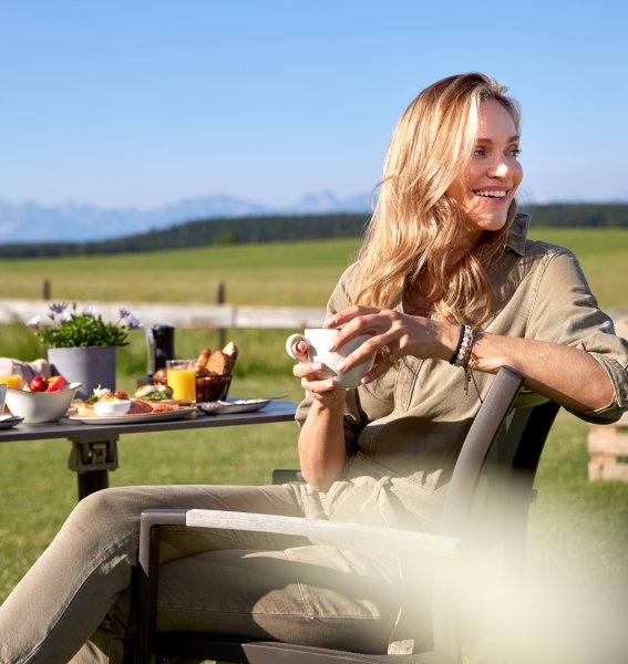 Eine Dame frühstückt auf der Terrasse im Weitblick Allgäu in Marktobderdorf.