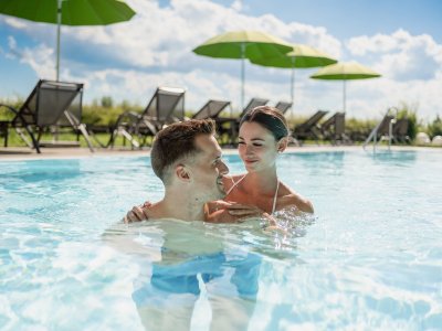 Ein Paar entspannt sich im Außenpool im Weitblick Allgäu in Marktoberdorf.