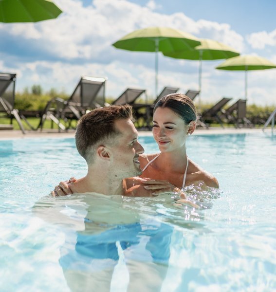 Ein Paar entspannt sich im Außenpool im Weitblick Allgäu in Marktoberdorf.