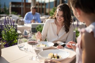 Zwei Damen essen an einem Tisch auf der Terrasse des Hotel Exquisit in Oberstdorf.