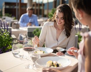Zwei Damen essen an einem Tisch auf der Terrasse des Hotel Exquisit in Oberstdorf.