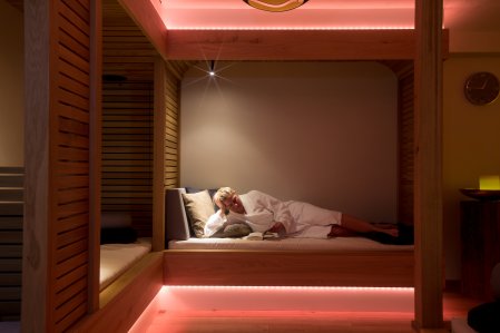 Hotel Hirsch Wellness Eine Frau liegt im Bademantel auf einem Wellnessbett im Wellnessbereich des Hotel Hirsch in Oberstaufen.