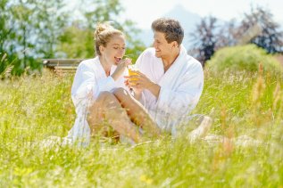 Ein Paar sitzt im Bademantel in einer Wiese im Landhotel Gockelwirt in Eisenberg.