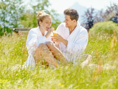 Ein Paar sitzt im Bademantel in einer Wiese im Landhotel Gockelwirt in Eisenberg.