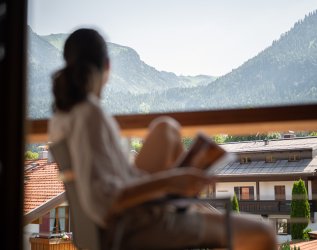 Eine Frau sitzt auf einem Balkon im Hotel Equisit in Oberstdorf und genießt die Aussicht.