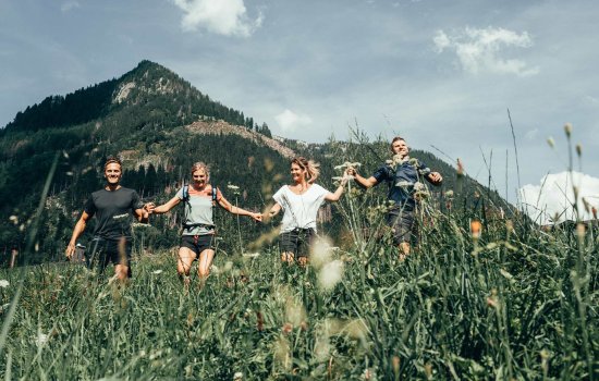 Eine Gruppe von Menschen beim Wandern bei den Alpzitt Chalets im Dorf in Burgberg.