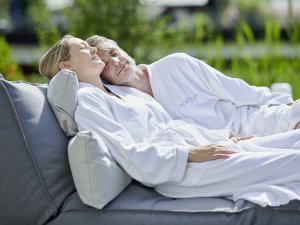 Ein Paar kuschelt im Bademantel im Garten des SCHÜLE`S Gesundheitsresort & SPA in Oberstdorf.