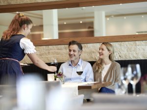 Ein Paar bekommt Wein eingeschenkt von einer Servicekraft des SCHÜLE`S Gesundheitsresort & SPA in Oberstdorf.