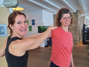 Die Fitnesstrainerin des Hotel Allgäu Sonne in Oberstaufen hilft der Autorin Silke Lorenz ihre Schulter zu dehnen.