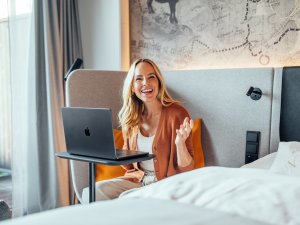 Eine FRau arbeitet vom Zimmer aus im A-ROSA Ifen Hotel im Kleinwalsertal.