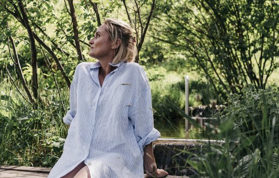 Eine Frau sitzt in der grünen Natur beim Naturhotel Chesa-Valisa in Hirschegg.