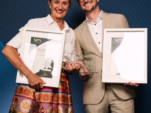 Zwei Personen vom Hotel Franks stehen vor einer offiziellen Award-Leinwand und halten die Preise sowie Auszeichnungen in der Hand