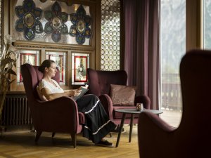 Eine Frau sitzt im Kaminsaal im Hotel Prinz-Luitpold-Bad in Bad Hindelang und liest