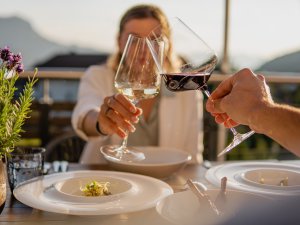 Zwei Personen im Alpin Cahlets in Oberjoch stoßen mit Weingläsern an